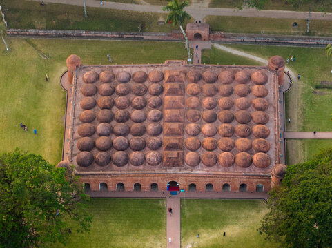 Aerial view of the historic Shat Gombuj Mosque with its distinctive multi-domed roof and terracotta brick architecture surrounded by green grounds in Bagerhat, Khulna Division, Bangladesh.