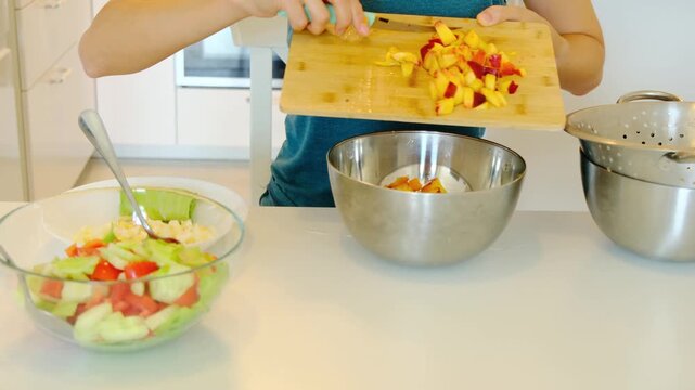 Woman slices colorful fresh fruits at kitchen table, preparing fruit salad, idea of healthy lifestyle and clean eating, home routine concept. ready for mixing into refreshing summer treat