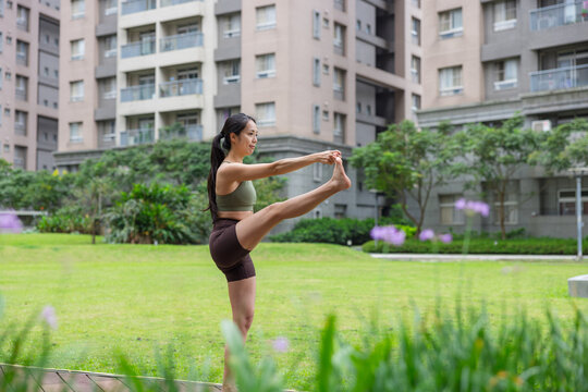 Woman doing extended hand to toe yoga pose outdoors