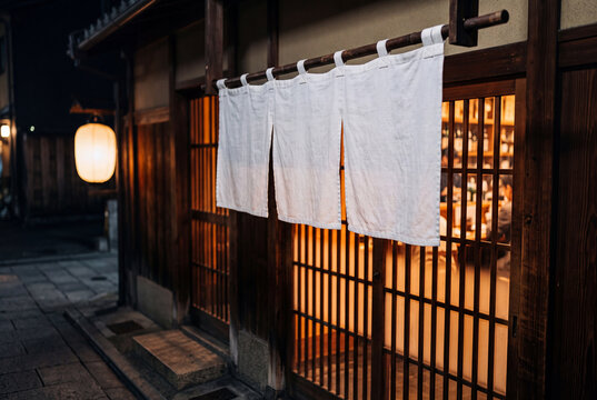 夜の和食店の入口に掛かる白い暖簾と温かな灯り