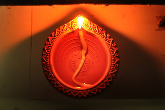 Traditional Diwali Diya Top View Glowing Terracotta Clay Oil Lamp with Burning Wick and Flame Close Up, Auspicious Indian Hindu Deepavali Festival Lights Celebration, Decorative Earthenware Design.