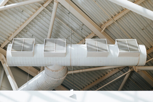 Four ventilation ducts are mounted on a white ceiling in a commercial building. The ducts are equipped with metal grilles for air distribution