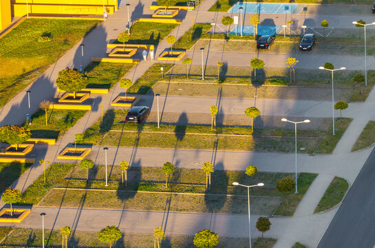 Aerial view of Morasko Campus parking lot with landscaped trees, paved walkways, and parked cars during the golden hour in Poznan, Greater Poland Voivod, Poland.