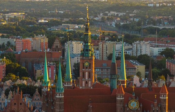 Aerial view of the Basilica of the Assumption of the Blessed Virgin Mary with brick tower and green spires, surrounded by historic urban rooftops of Gdansk, Pomeranian Voivodeship, Poland.
