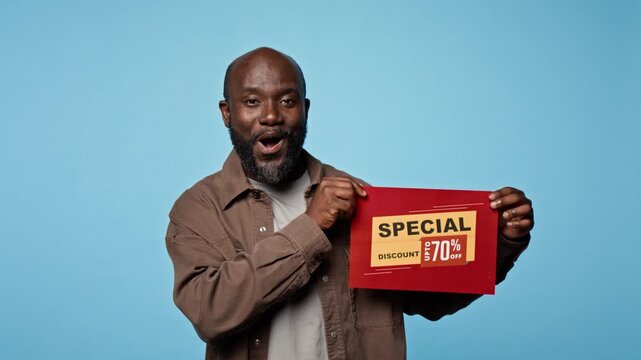 Portrait of African American man holding discount sale sign, reacting excitedly. Video suitable for retail marketing promotions, seasonal clearance commercials and shopping ads
