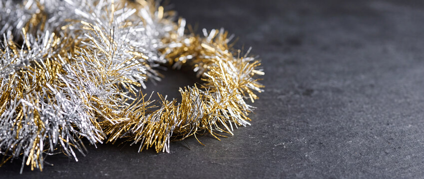 Gold and silver tinsel garland on dark slate background for christmas and holiday decor