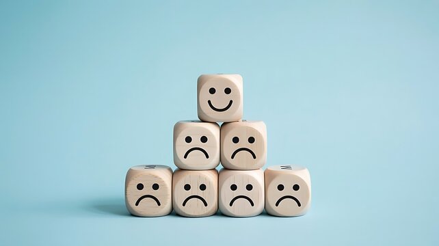 Wooden blocks arranged in a pyramid showing a single happy face icon sitting above many sad faces representing negative feedback and customer dissatisfaction