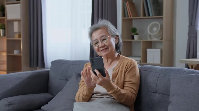 Happy elderly woman smiling while using smartphone at home, enjoying online communication, mobile technology and an active independent lifestyle after retirement.