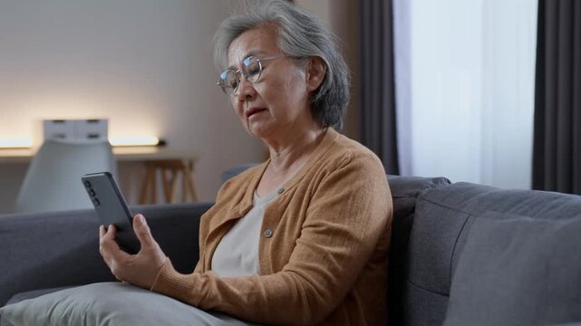 Senior woman looking at smartphone while relaxing on sofa at home, enjoying mobile technology, digital communication and an independent lifestyle in retirement.