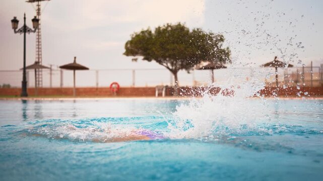 Professional swimmer training butterfly stroke in outdoor pool with clear blue water, demonstrating athletic power, endurance, and technique during a rigorous workout session