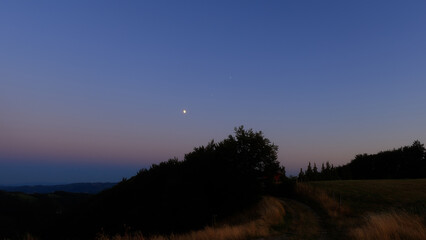 Moon on a twilight sky with stars, planets and landscape mountain silhouettes. © astrosystem
