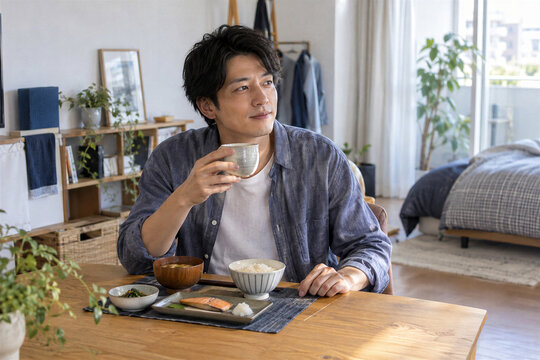 自宅の食卓で和朝食とお茶を楽しむ一人暮らしの日本人男性