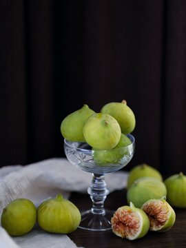 Fresh green figs in vintage glass cup, sliced organic fig on dark background