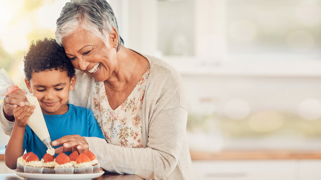 Grandmother helping grandson decorate strawberry cupcakes with blurred kitchen background banner.