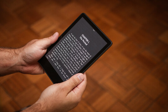 A man holding a Ebook reader. A man reading a book from an ebook reader. Reading a book on an ebook reader