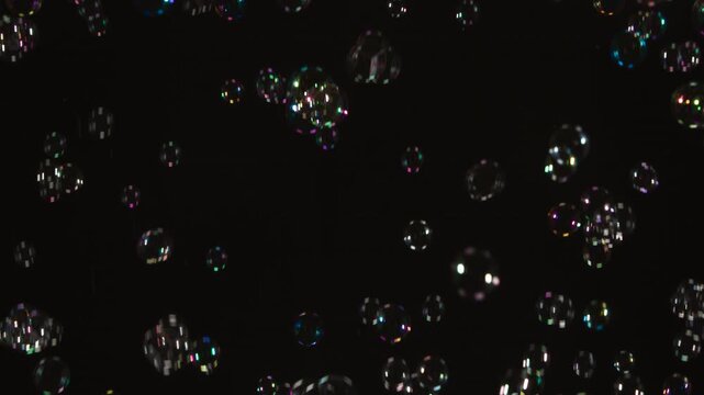 Flight of Many Soap Bubbles. A large number of soap bubbles moving in one direction against a black background. Great for use in blending