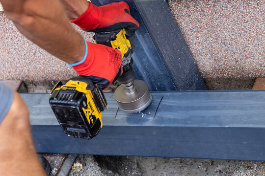 Fuerstenwalde, Brandenburg, Germany-August 17, 2026: Worker drilling a large hole into steel beam with DeWalt tool