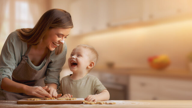 Mother and child laughing with flour on noses baking cookies with blurred kitchen background banner.