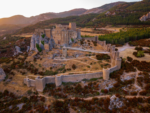Aerial sunset view of Loarre Castle, its fortified medieval walls and surrounding foothills in Aragon, Spain.