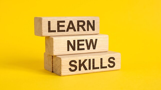 Learn new skills text on wooden blocks, educational growth concept on yellow background, professional development and career training