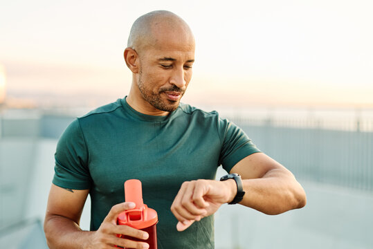 Portrait opf a young man prepering to exercise and run and looking at watch in sportwear posing for a portrait outdoors
