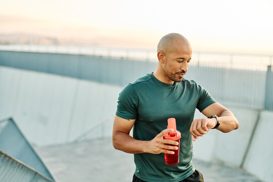 Portrait opf a young man prepering to exercise and run and looking at watch in sportwear posing for a portrait outdoors