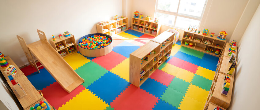 A bright indoor children's play area with slide, ball pit, storage shelves and colorful foam floor mats.