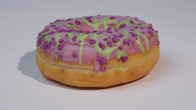 Enjoying a donut with frosting and sprinkles, side view, spinning donut, white background