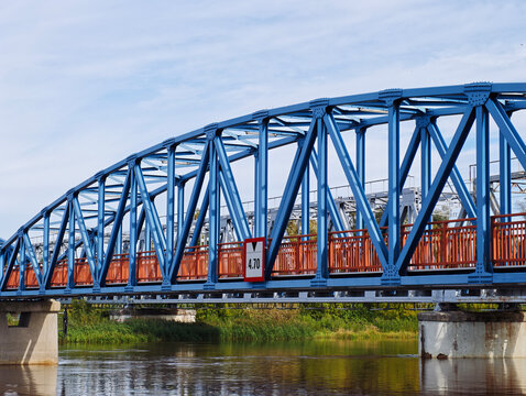Blue Geometric Steel Truss Bridge Over River - featuring riveted beams, geometric framework, a 4.70 clearance marker and adjacent transport infrastructure.
