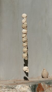 Ceramic skull column floating in a vertical line over a gritty stone step, featuring a chalky bisque texture for craft and art concepts, with copy space