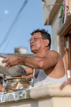 Man placing a metal vessel of kheer on a stone parapet during sharad purnima, quiet and atmospheric scene for dairy campaigns