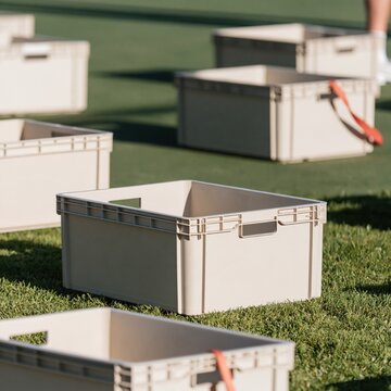 Grey sorting crates arranged in a pattern on a green field, featuring a red accent strap for charitable donation and nonprofit fundraising