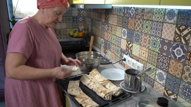 Senior woman cooking food at home. Make pies with cottage cheese in pita dough. Cook and talk.