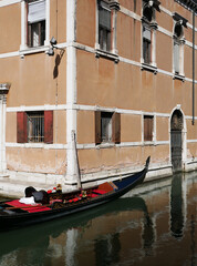 a still venetian gondola boat on a canal in Venezia (Venice), Italy,  in front of a building © Isabella