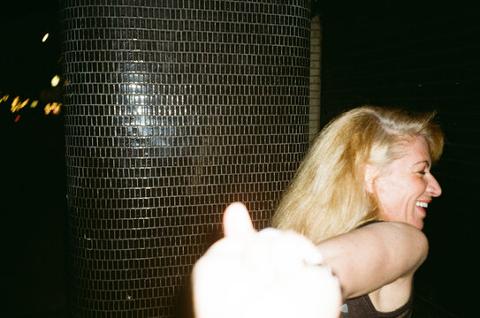 Laughing woman beside mosaic column at night