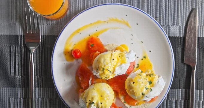 Delicious eggs benedict served with smoked salmon, hollandaise sauce, and fresh orange juice on a plate. Tasty morning breakfast meal at luxury hotel restaurant. Brunch vacation concept.