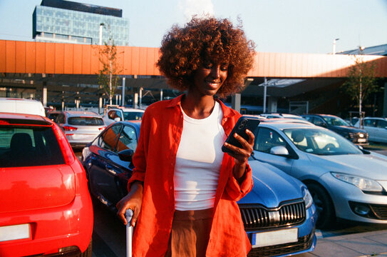 Woman checking phone beside suitcase during travel, film photo