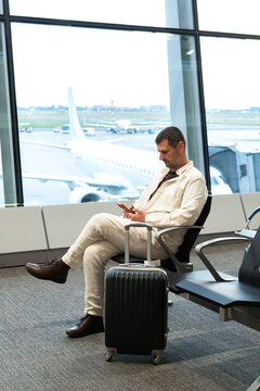 A man scrolls his phone in an airport departure lounge