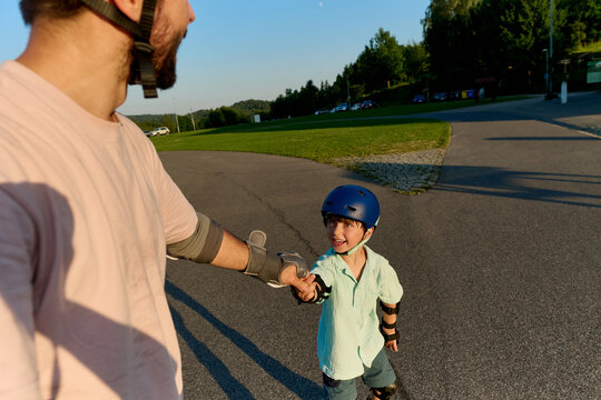 Father Holding His Son's Hand While Learning to Roller Skate