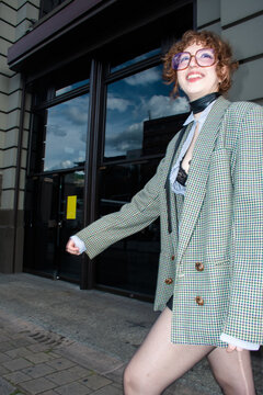 Smiling Person Walks Outside a Building Wearing a Large Blazer