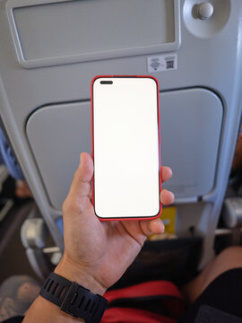 Hand holding smartphone with blank screen on airplane