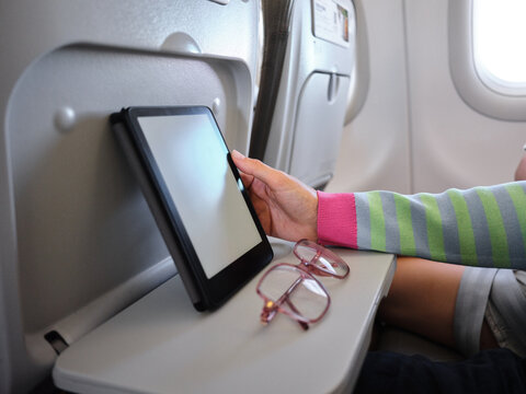 Passenger reading ebook on tablet during airplane flight
