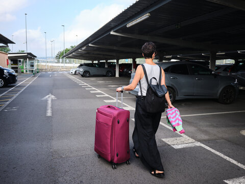 Woman pulling suitcase in airport parking lot