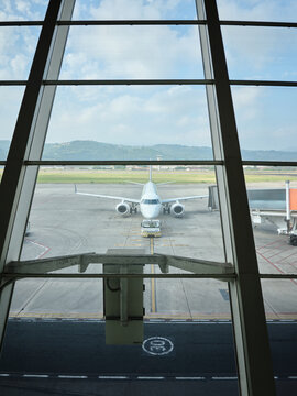 Airplane on airport tarmac viewed through terminal window