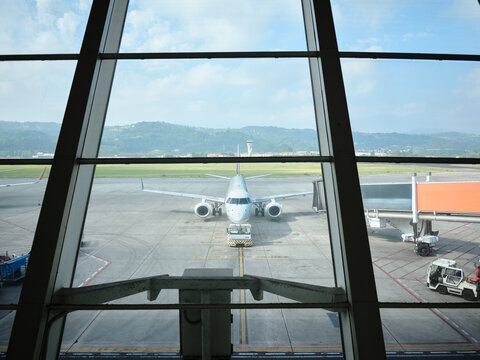 Airplane on airport tarmac viewed through terminal window