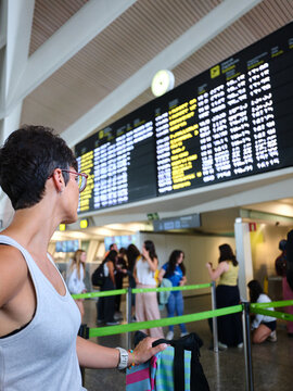 Traveler checking flight departure information board at airport