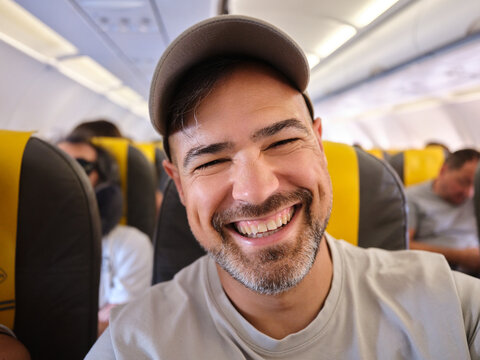 Happy man traveling on airplane, enjoying vacation trip