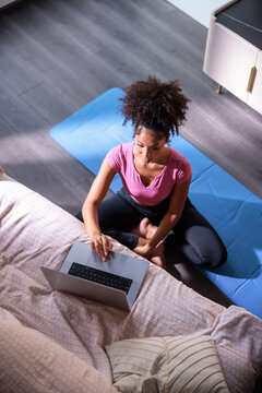 Woman sitting on a yoga mat using a laptop