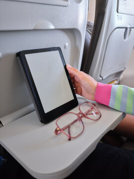 Passenger reading e reader on airplane tray table