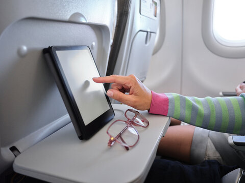 Passenger using digital tablet during airplane flight
